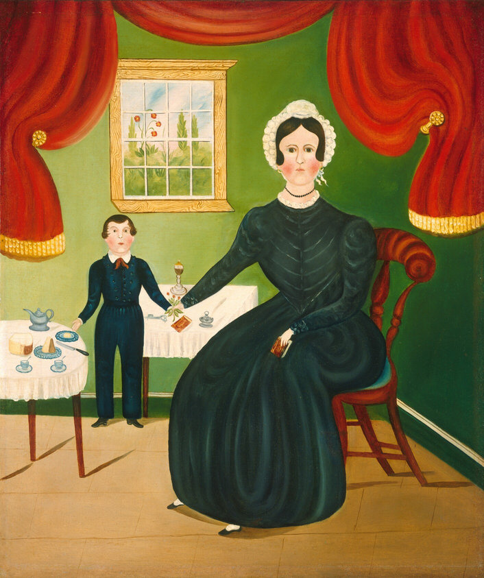 The image shows a seated woman and a standing boy beside her. The woman is sitting on a wooden chair, with her right hand resting on a small table and her left hand holding a small book. She has dark hair styled in an updo and wears a long, dark dress with long sleeves and a pearl necklace. The boy is standing beside her, wearing a dark suit with shiny buttons and a bow tie. In front of them is a table covered with a white tablecloth, holding cakes, cups, a teapot, and a spoon. The background has a green wall with a window showing greenery and flowers outside, framed with a wooden frame. Red drapes with gold accents hang on either side of the window.