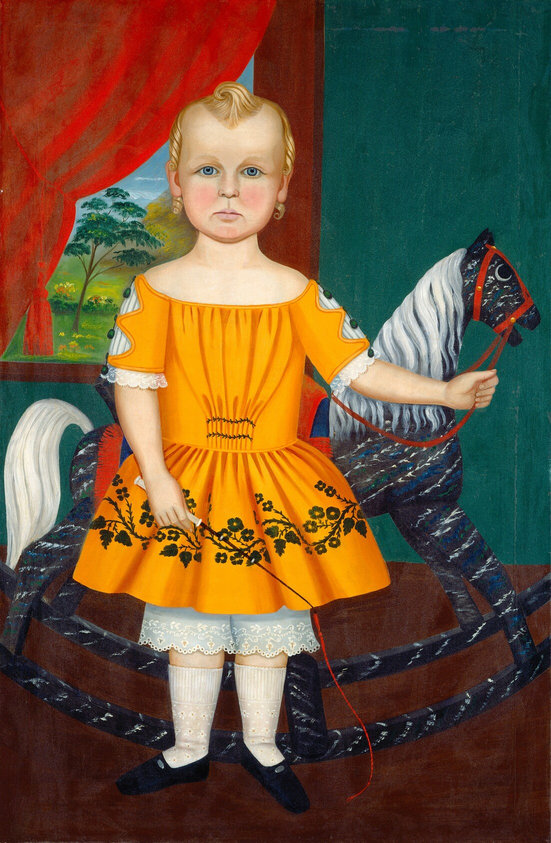 The image shows a young child standing next to a rocking horse. The child is standing upright with one hand resting on the rocking horse's head and the other hand holding a whip. The child has fair skin, blue eyes, and short blonde hair with a small curl at the top. The child wears an orange dress with floral patterns, white lace-trimmed pantaloons, white stockings, and black shoes. The background includes red drapery on the left side and a bright landscape visible through a window, as well as a deep green hue on the right side.