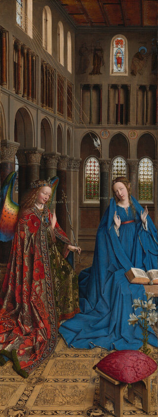 A woman and winged angel, both with pale, peach skin, are situated in a church interior in this tall, narrow painting. To our left, the angel has long, blond, curly hair, smooth skin, and is smiling. The wings are outlined in royal blue, and they blend from blue to green to yellow to crimson. The angel holds one hand, closer to us, up at chest height with the index finger subtly pointing upward. Holding a long scepter in the other hand, the angel angles their body toward the woman to our right. The angel wears a gold jewel and pearl-encrusted crown and a jeweled long, voluminous robe in scarlet-red and shimmering gold brocade. The neck and along the opening down the front are lined with pearls and jewels. The angel looks toward the woman, who wears a royal-blue dress tied with a red belt at the high waist. Her long brown hair is tied back but one tendril falls over her left shoulder, to our right. She kneels facing us with her raised hands facing outward. Her head is tipped a bit to our left, and she looks up and into the distance to our right with lips slightly parted. She kneels behind a book lying open on a low table. A vase of white lilies and a red cushion lies on the floor in front of the table, close to us. The floor is decorated with people and scenes outlined in black and set into square panels, as if inlaid with wood. The church behind and above the people has a row of tall, narrow arches with bull’s-eye glass windows. A walkway lined with columns runs above the arches, and sunlight comes in through arched windows under the flat wood ceiling. A white dove flies toward the woman on gold lines from a window at the upper left of the painting. Latin words painted in gold capital letters are exchanged between the people. The angel says, “AVE GRA PLENA.” The letters of the woman’s response are painted upside down and backward: “ECCE ANCILLA DNI.”