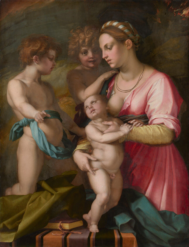 Two nude young boys and a young woman holding a standing infant are tightly grouped around a table, almost filling this vertical painting. They all have pale skin tinged with pink. The woman is shown from the knees up, and she stands at the front, right corner of the table, which spans most of the composition. Facing our left in profile, her auburn-brown hair is pulled back and wrapped with a slate-blue ribbon, and is wound around the crown of her head. She looks down with dark eyes under thin brows. She has a long nose, and her full, dusty rose-pink lips are closed. Two thin cords hang like necklaces just above the neckline of her carnation-pink gown, which is unbuttoned to reveal one bare breast. The plump infant stands at the center of the group. The woman holds him close to her body, but he turns his face away to look at the young boy on our left. That child faces our right in profile and has wavy, copper-red hair. He is nude except for a blue sash, which is tied once tightly around his waist and then wrapped so a loose hoop hangs down over his belly. His right knee, closer to us, rests on an olive-green cloth crumpled on the table beneath him. He leans back slightly, with his belly pushed forward, and looks down at the infant while pointing to us with his closest hand. A third child, with unruly honey-blond hair, stands facing us from the back of the group, so is seen between the woman and the pointing child. The child at the back of the group touches the woman’s shoulder with one hand, looking straight at us with mouth slightly open. A burgundy-red sash is visible around the waist. Near the bottom edge of the painting, the tabletop is covered with a pumpkin-orange cloth striped with plum-purple and black. A book rests near the baby’s feet and is partially covered by the green cloth to our left. A peacock-blue cloth is bunched on the right half of the table and hangs off that side, obscuring the woman’s knees. The background is painted with broad strokes and swirls of brown and flint blue, with flickers of red and gold in the upper right.